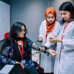 Estudantes de Medicina praticam a aferição da pressão arterial em uma sala de treinamento universitário.