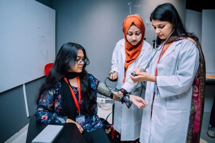 Estudantes de Medicina praticam a aferição da pressão arterial em uma sala de treinamento universitário.