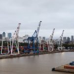 Contêineres e guindastes em um porto diante do skyline de Buenos Aires.