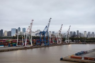 Contêineres e guindastes em um porto diante do skyline de Buenos Aires.